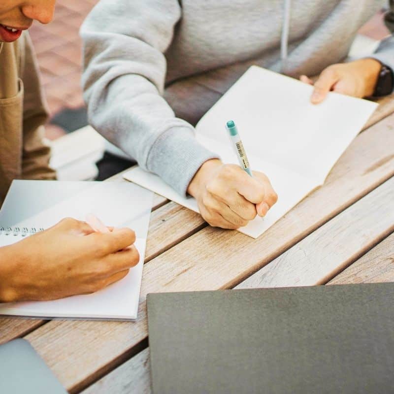 Two people writing in notebooks. Students who fail to launch can get a second chance at Live Strong House, Utah