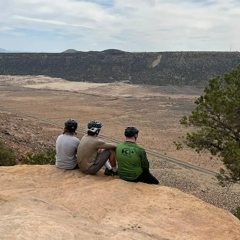 3 young men sit together on a desert hike