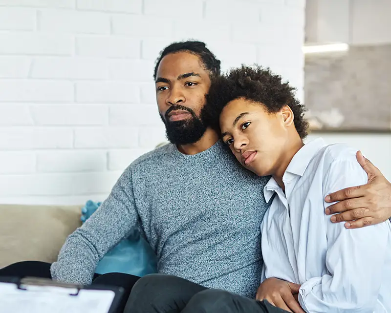 a father wraps his arm around his son's shoulder