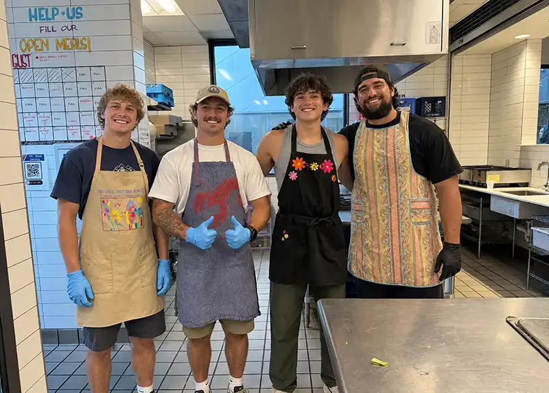 a group of young men pose for a picture while helping in a commercial kitchen